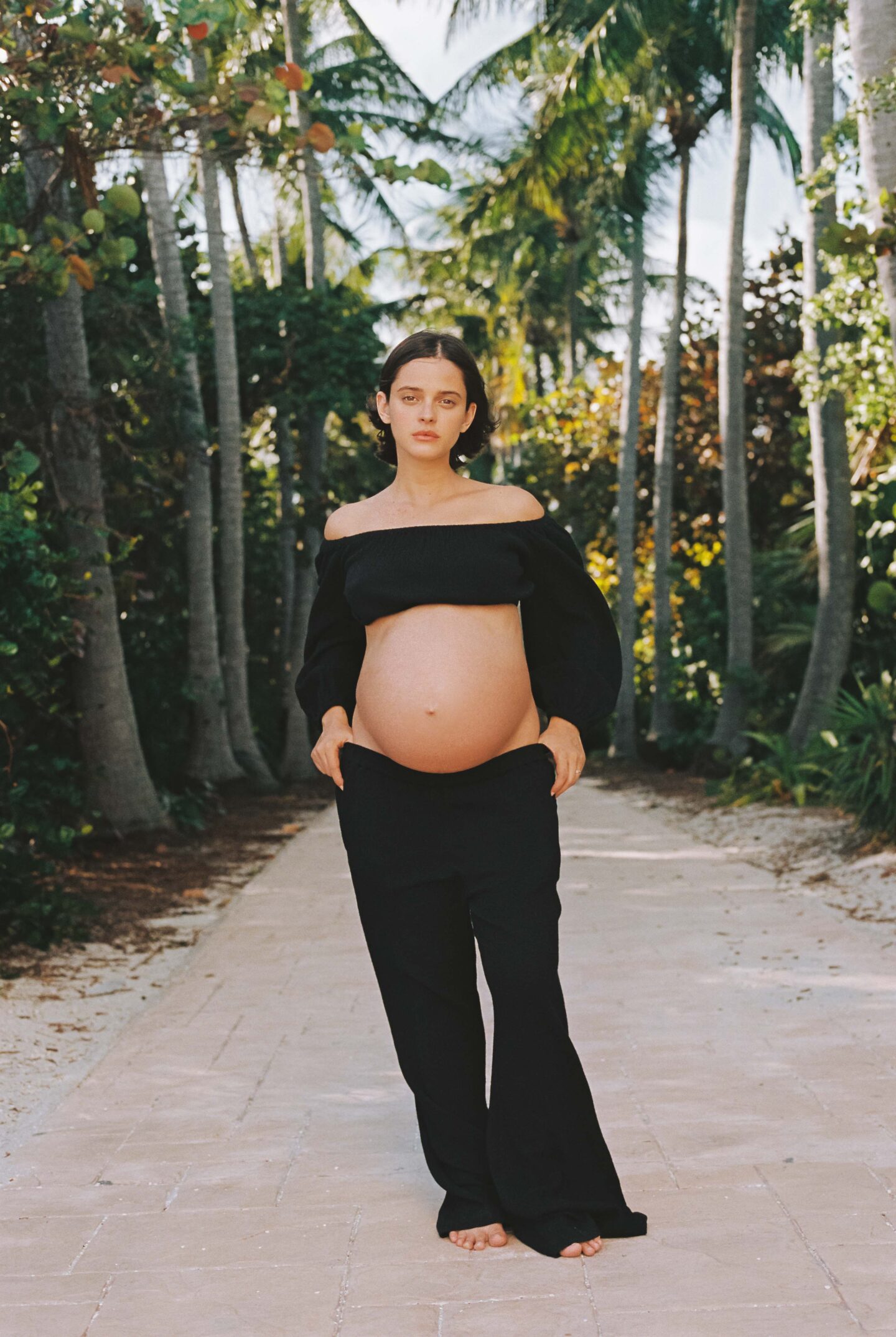 pregnant woman wearing a crop top in a tropical location