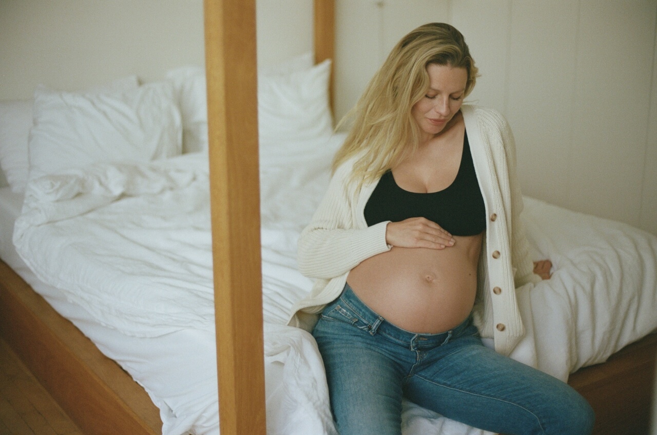 pregnant woman sitting on edge of bed