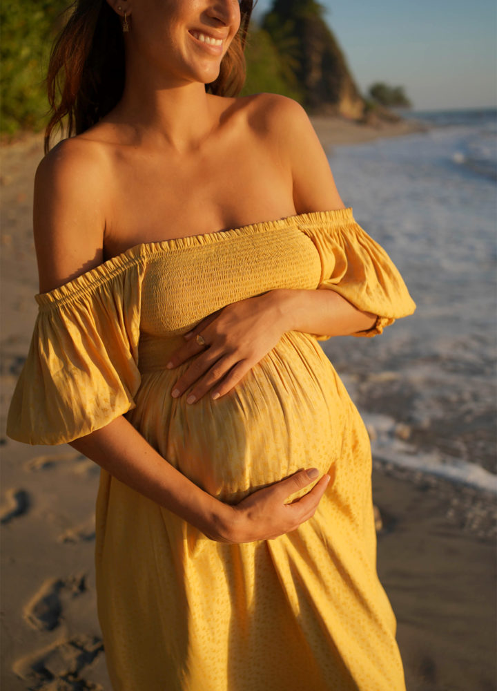 pregnant woman wearing yellow dress on a beach