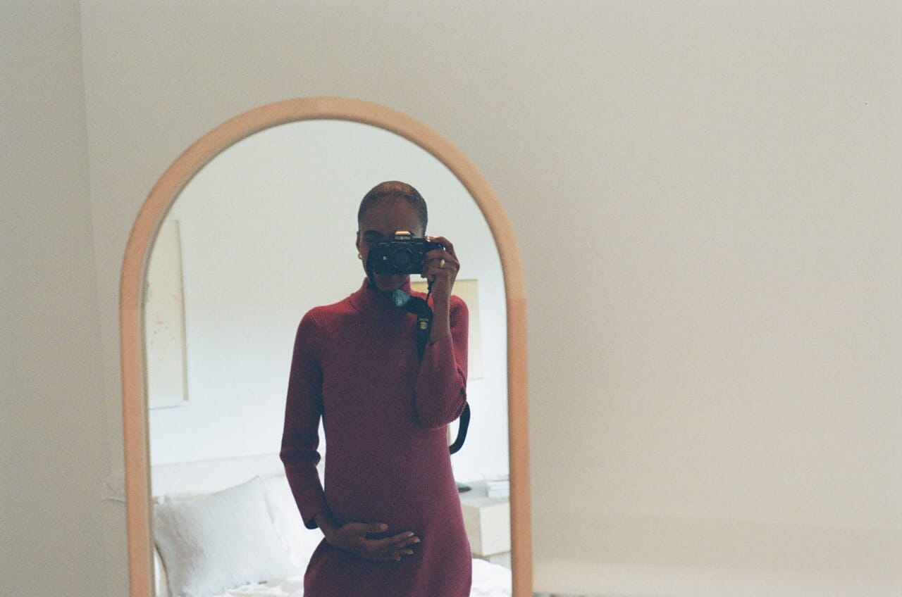 pregnant woman taking selfie with film camera