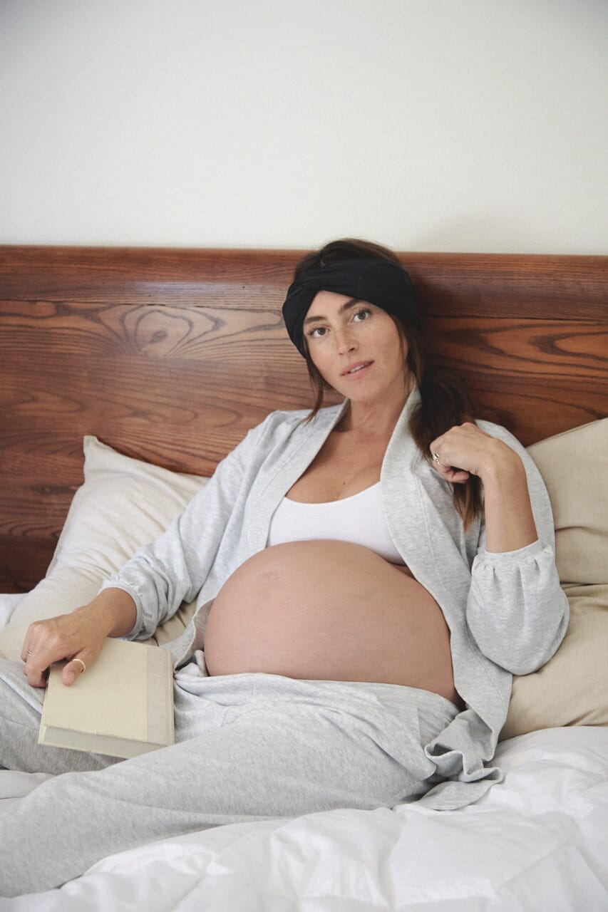 pregnant woman laying in bed reading