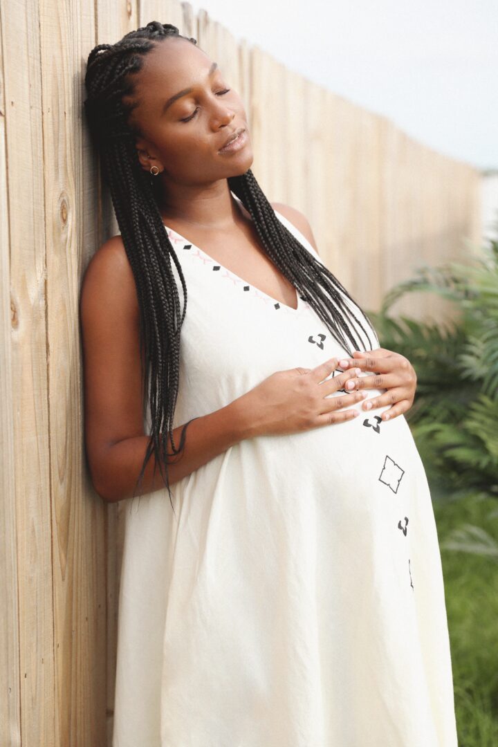 pregnant woman leaning against a fence