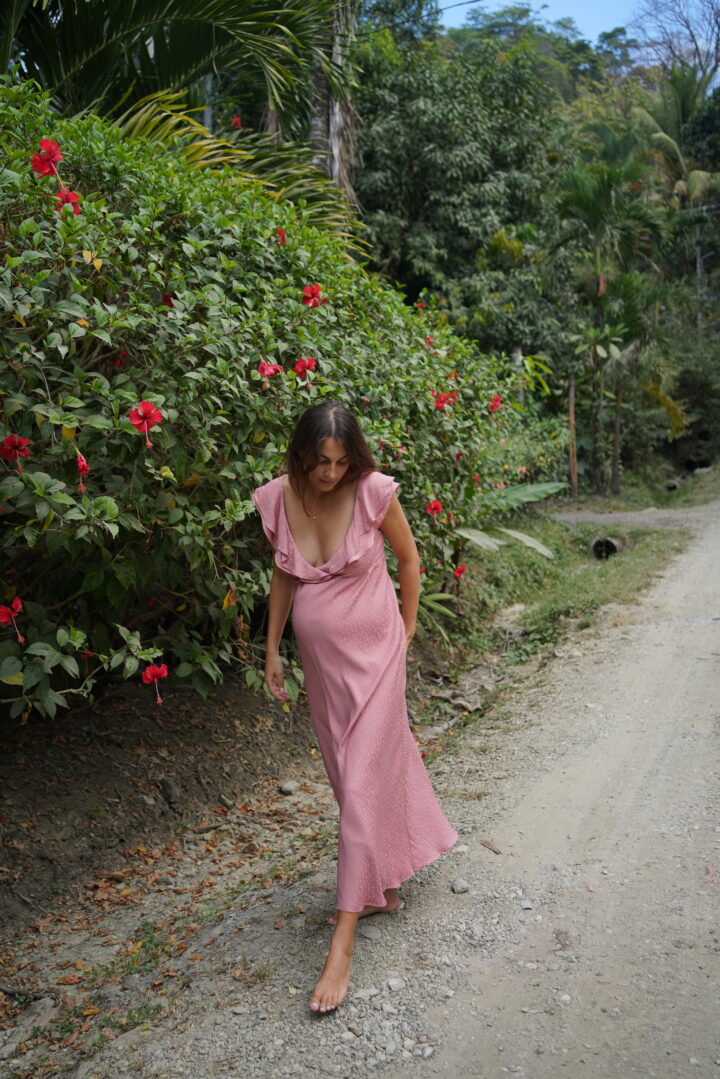 pregnant woman in pink dress walking barefoot