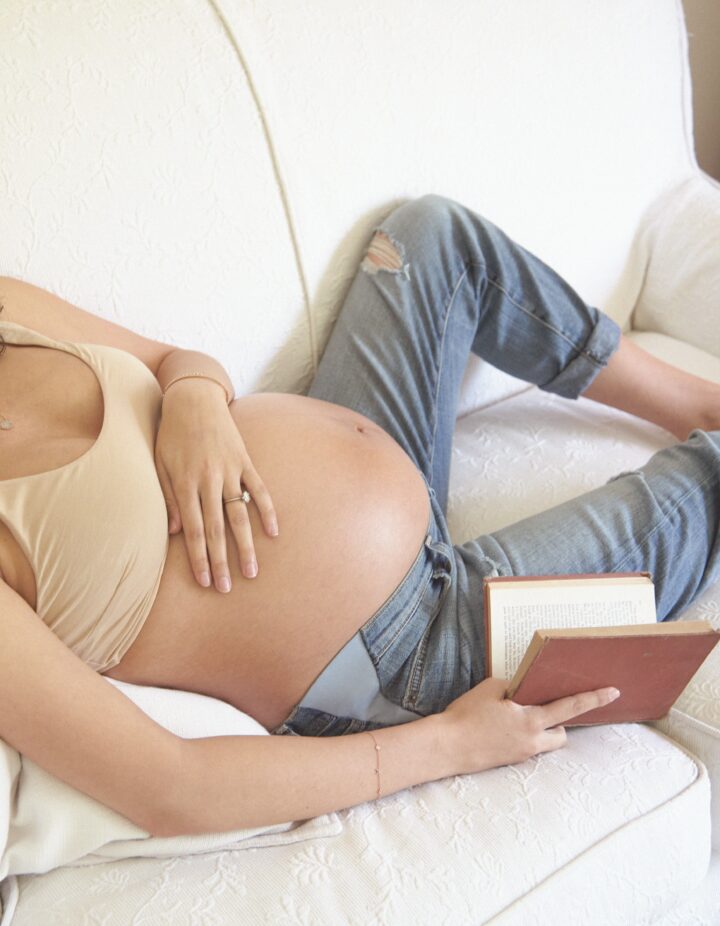 Pregnant Woman reading a book with belly out
