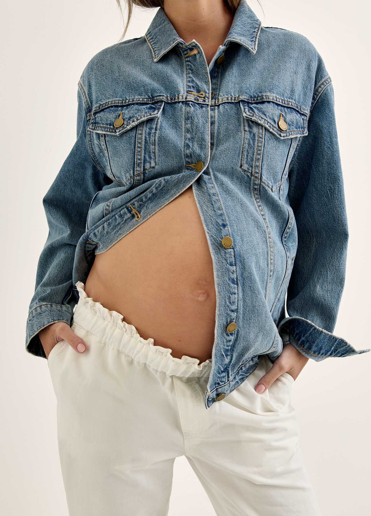 pregnant belly peaking through a denim jacket
