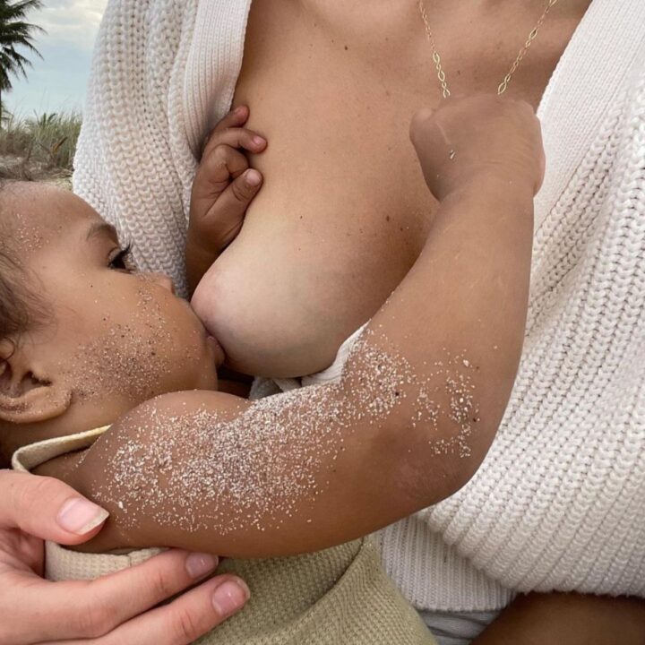 Woman breastfeeding baby covered in sand