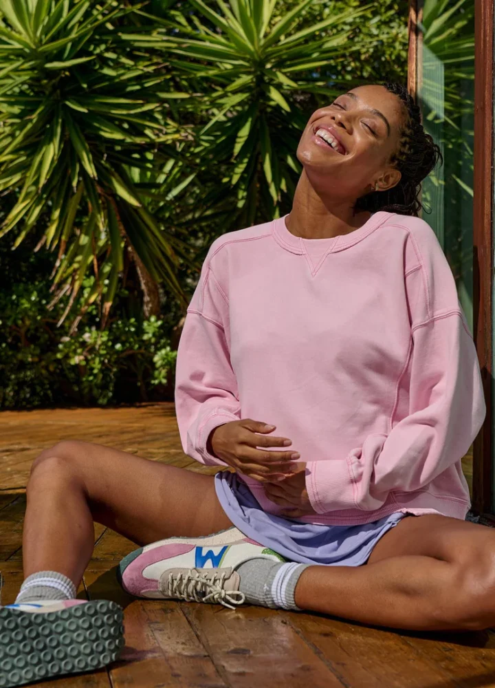 Pregnant Woman embracing her belly in a pink sweatshirt