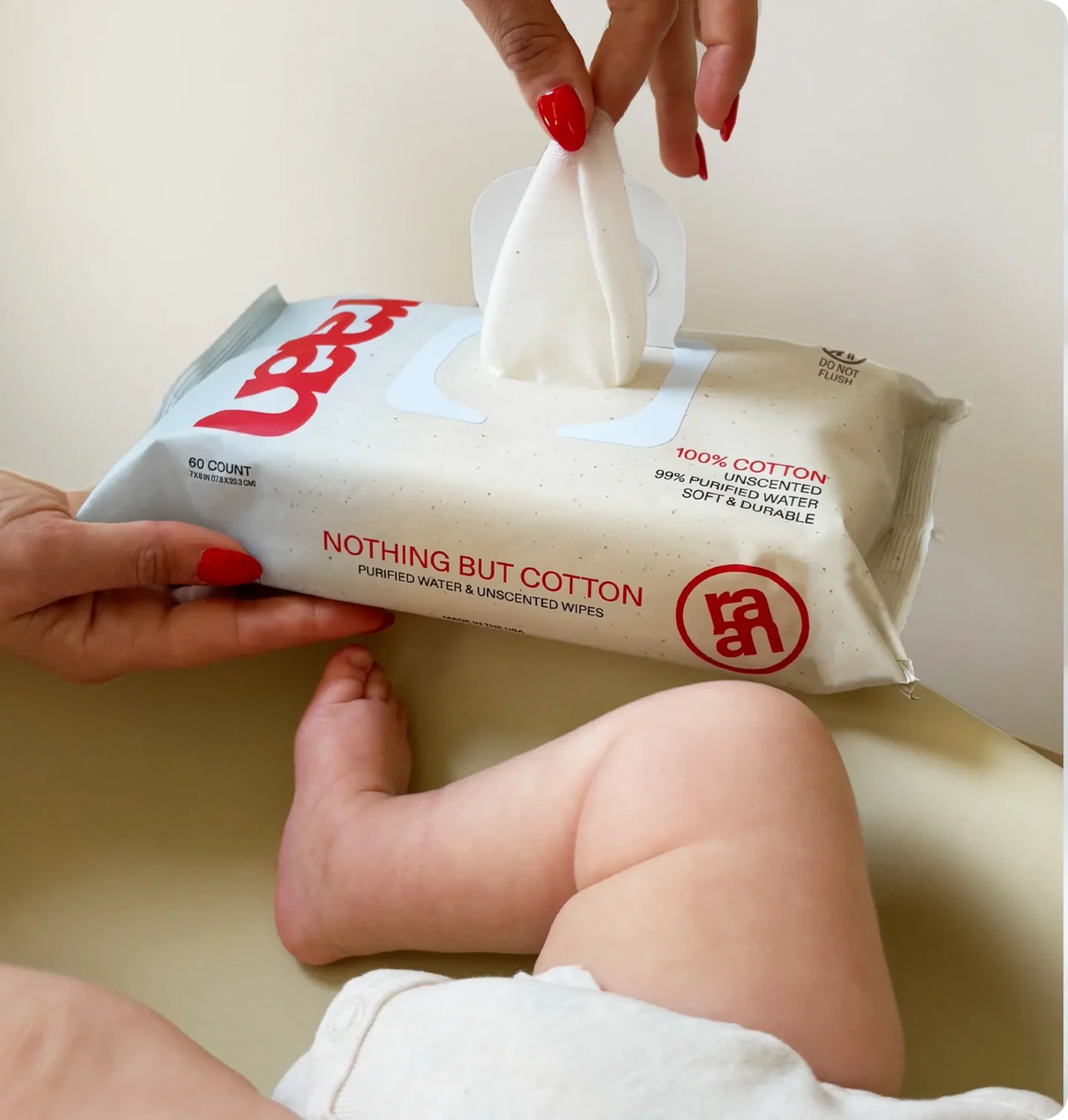 baby wipes being pulled out of container, baby partially pictured